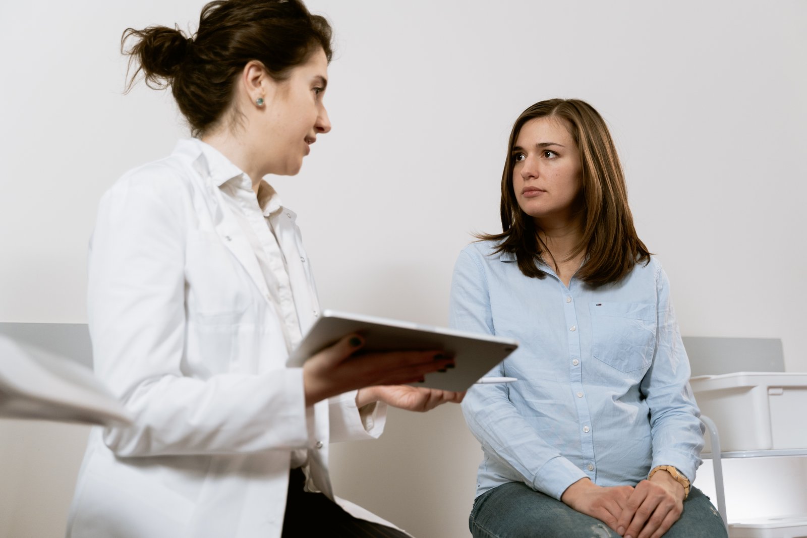O femeie stă la ginecolog și vorbește cu ea.